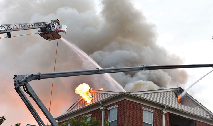 Ladder 117 operates a master stream into a collapsed portion of the roof and Engine 148 directs a master stream into the roof vent opening in the attic space. This photo was taken after the Mayday was secured, showing fire conditions in the attic.