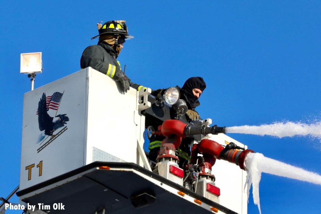 Firefighters in a tower ladder bucket flowing water