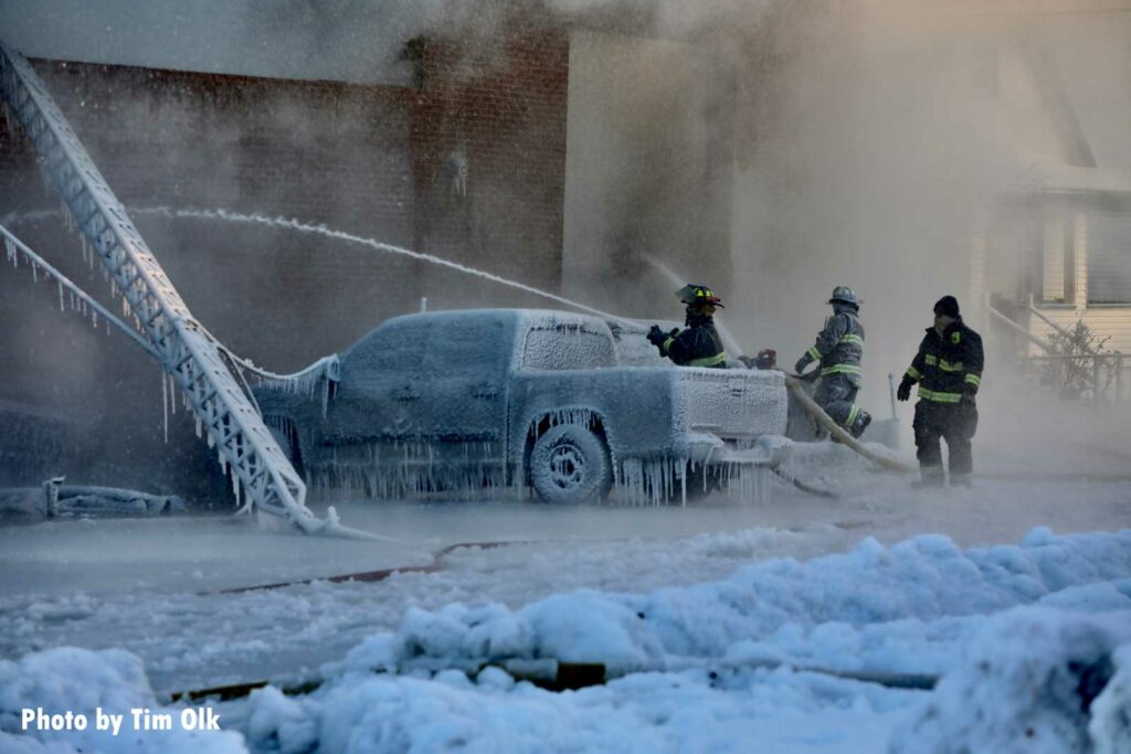 Icicles cover a vehicle as firefighters train a hoseline on the fire