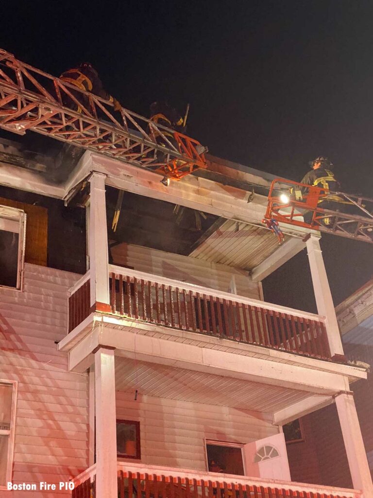 Two firefighters on aerial ladders at the scene of the fire in Boston