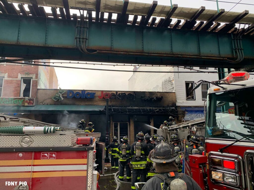 Burned out building with FDNY firefighters on scene under the elevated rail in Queens