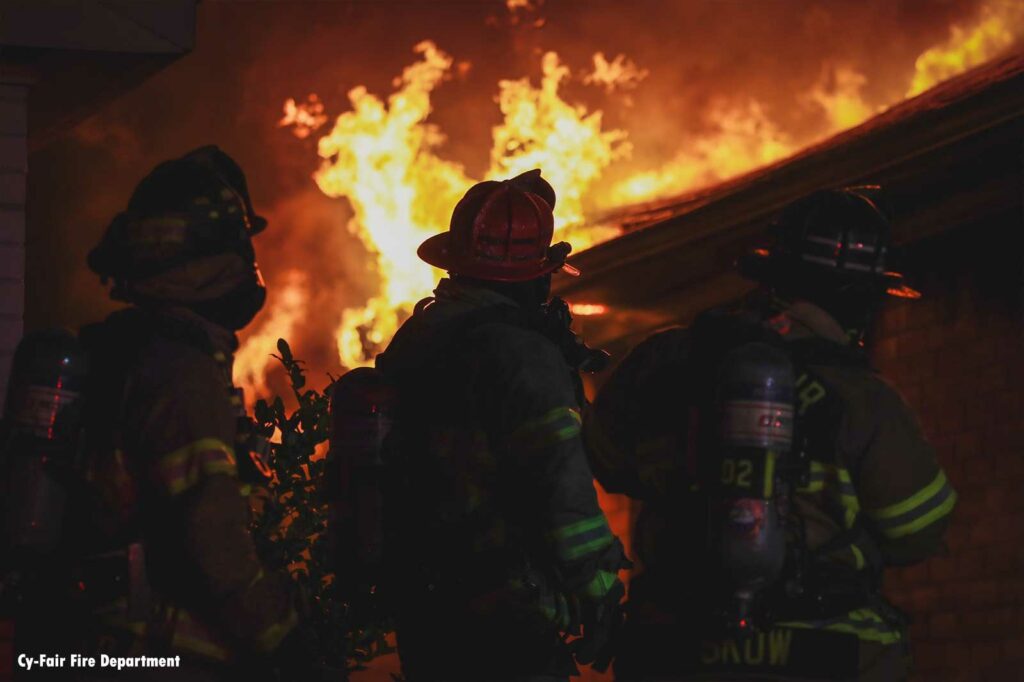 Firefighters in the foreground with flames raging in the background