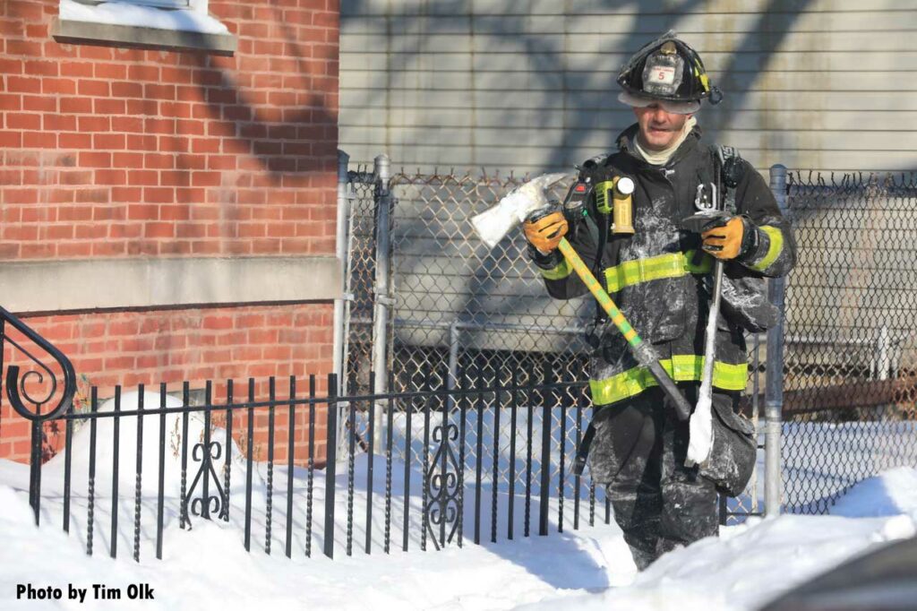 Firefighter carrying an ax and a halligan at fire