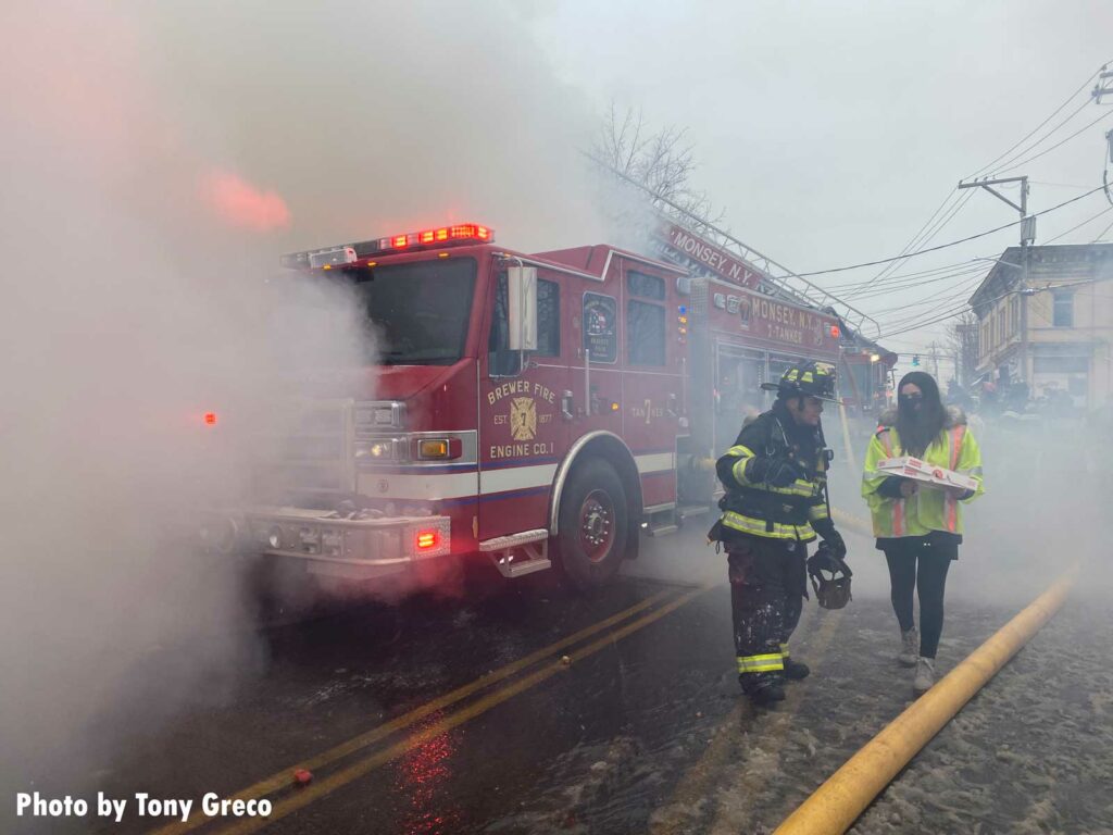 Firefighters at the scene of a Monsey fire, with rig partly enveloped by smoke