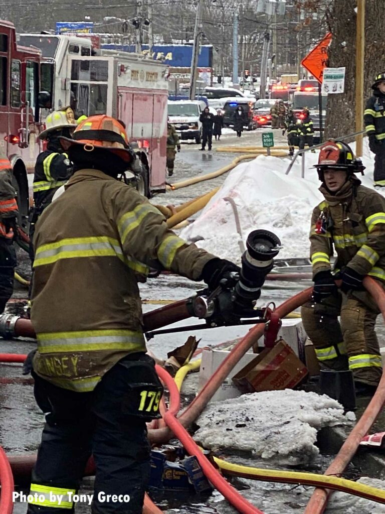 Firefighters move hoseline at the Monsey fire scene