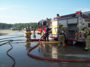 Firefighters pumping water on a fire apparatus