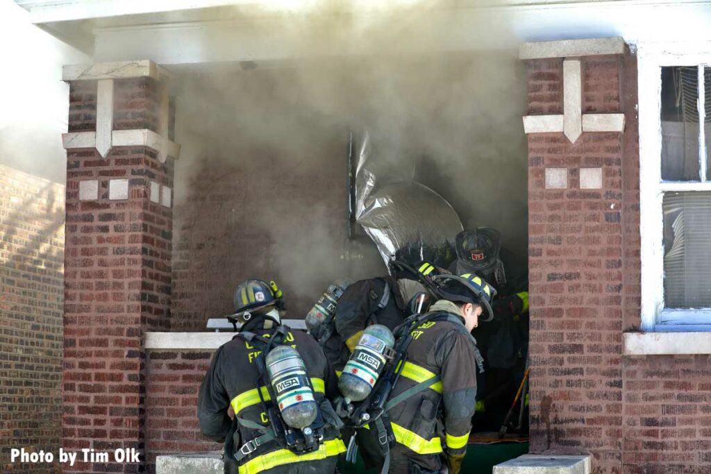 Firefighters push into the interior of a home with a handline