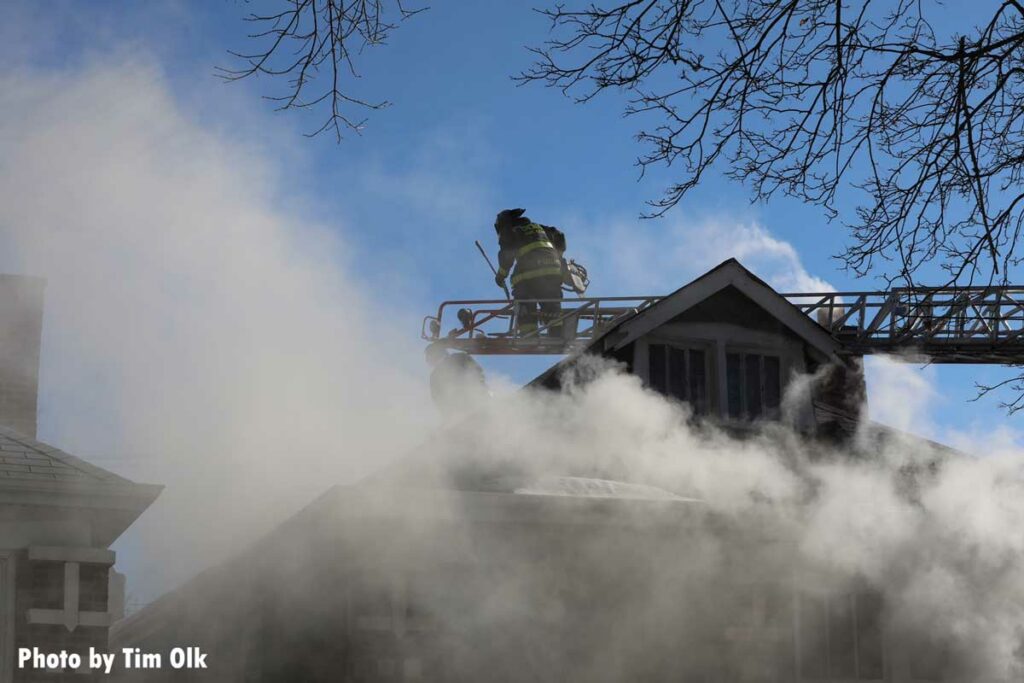 Smoke drifts up from a fire as a Chicago firefighter operates on an aerial ladder