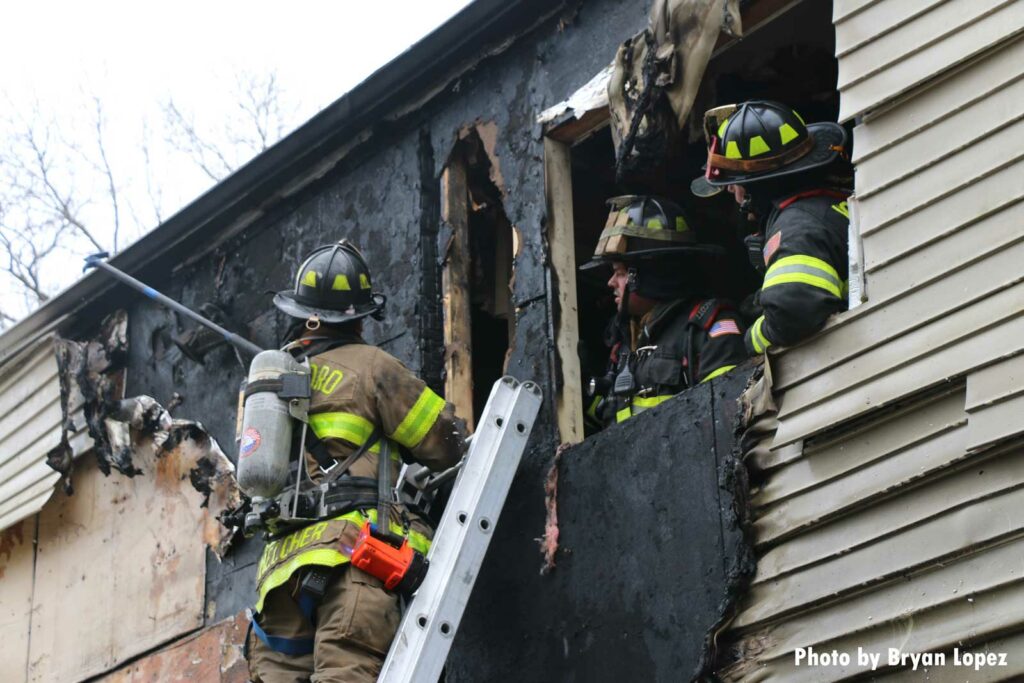 Firefighters work on the exterior of a charred building