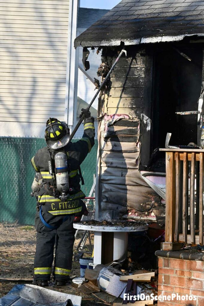 Firefighter with a pike pole performs overhaul on burning building