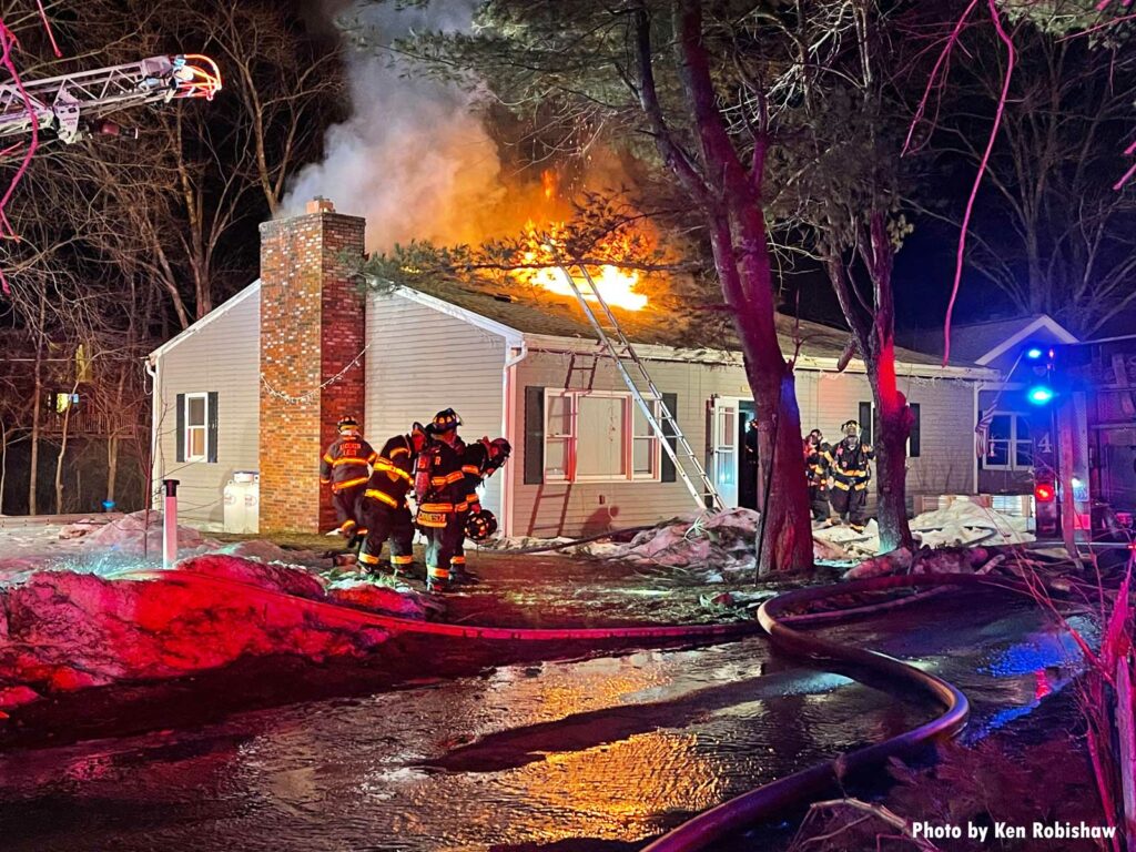 Aerial ladder and ground ladder on house in Andover with fire showing through the roof