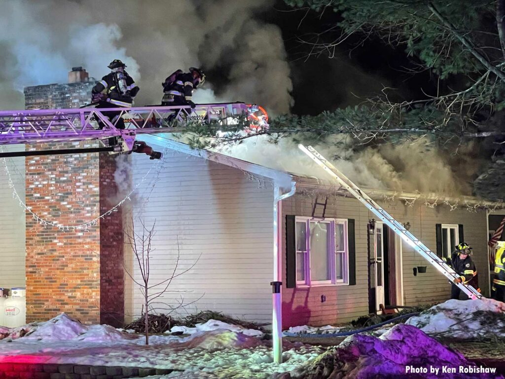 Firefighters on an aerial ladder and one firefighter with ground ladder at Andover MA fire