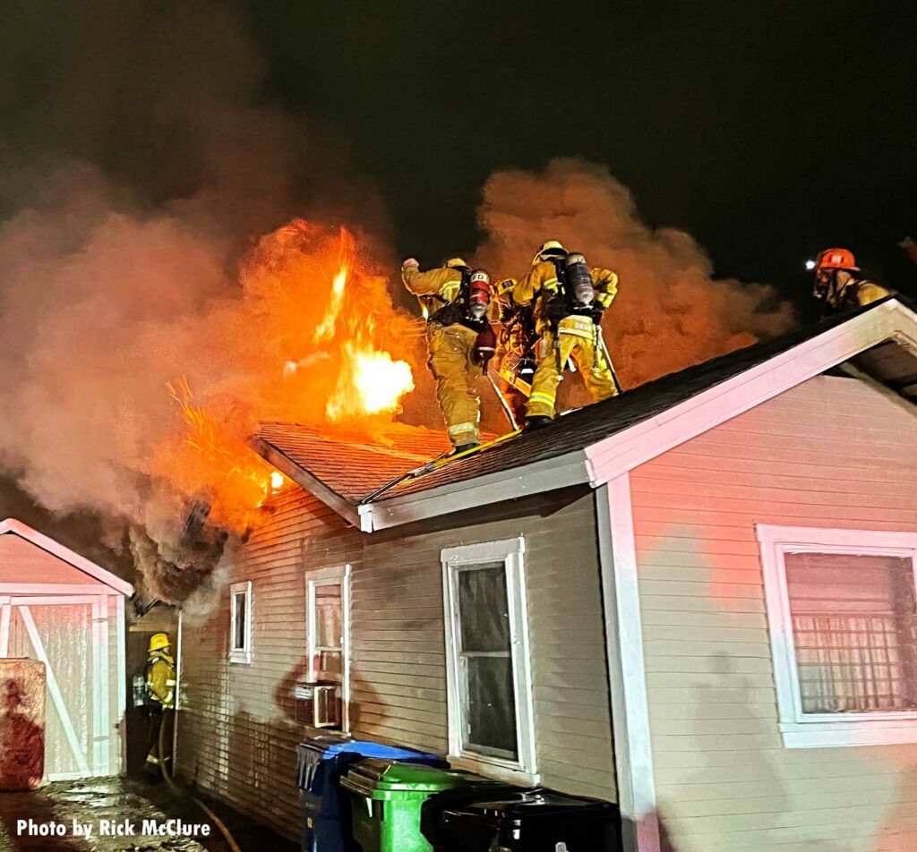 LAFD firefighters operate on the roof as flames shoot up