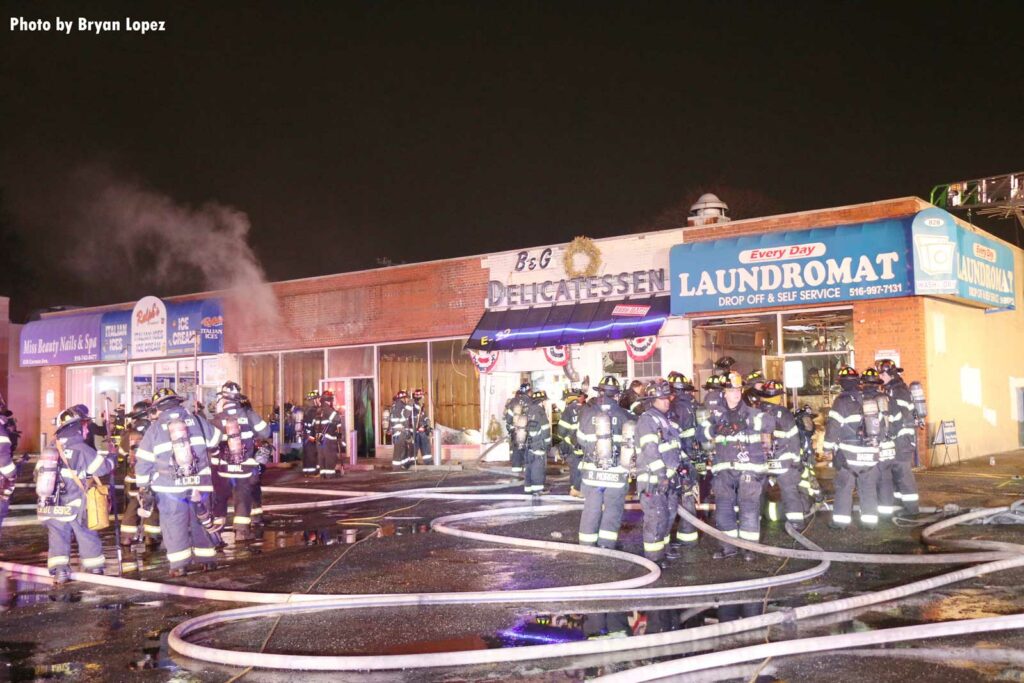 Firefighters with hoseline outside fire that impacted multiple businesses