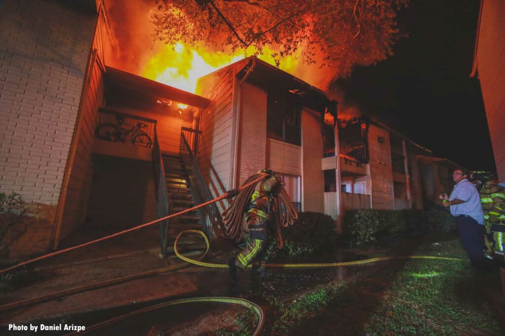 Firefighter stretches a line in between buildings at apartment complex fire in Houston