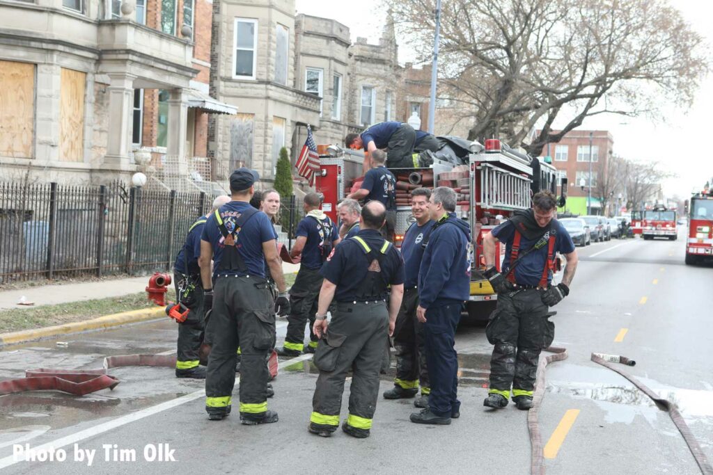 Chicago firefighters discuss the incident on the back step of an apparatus