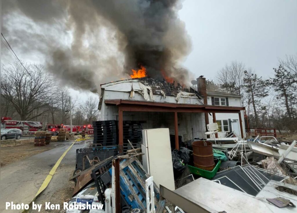 Smoke and fire from the roof of the building with various folderol in the yard