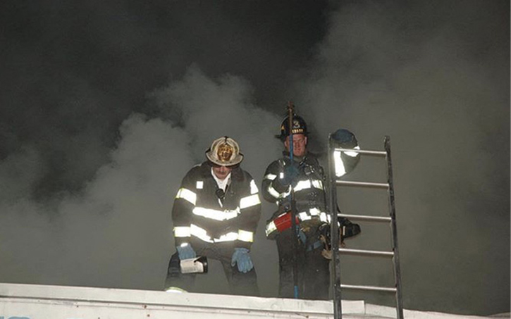 The battalion chief assigned to the roof division communicates with the incident commander on the conditions and progress of crews working topside.