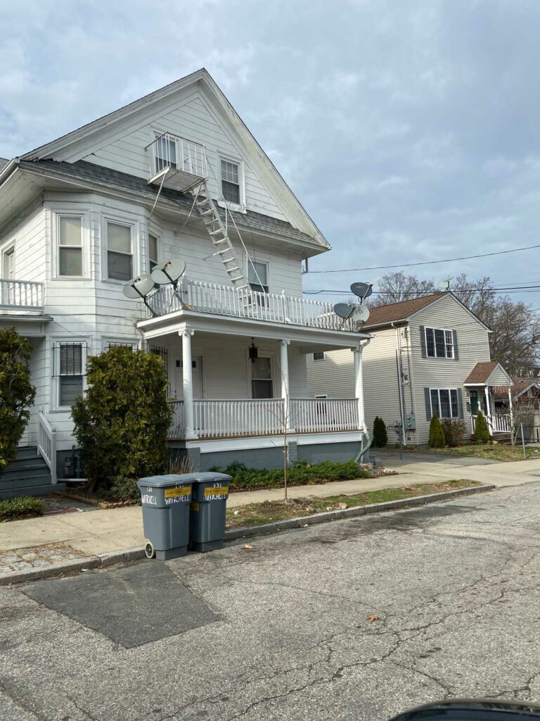 A porch with a fire escape and multiple TV dishes