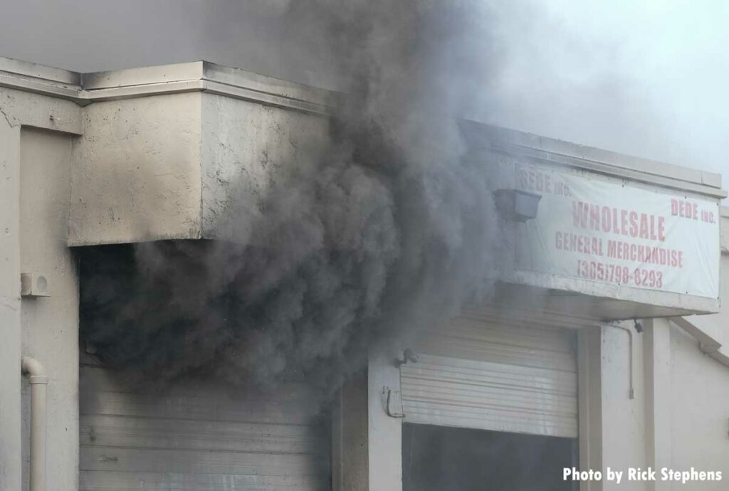 Smoke shoots out from a doorway at the warehouse