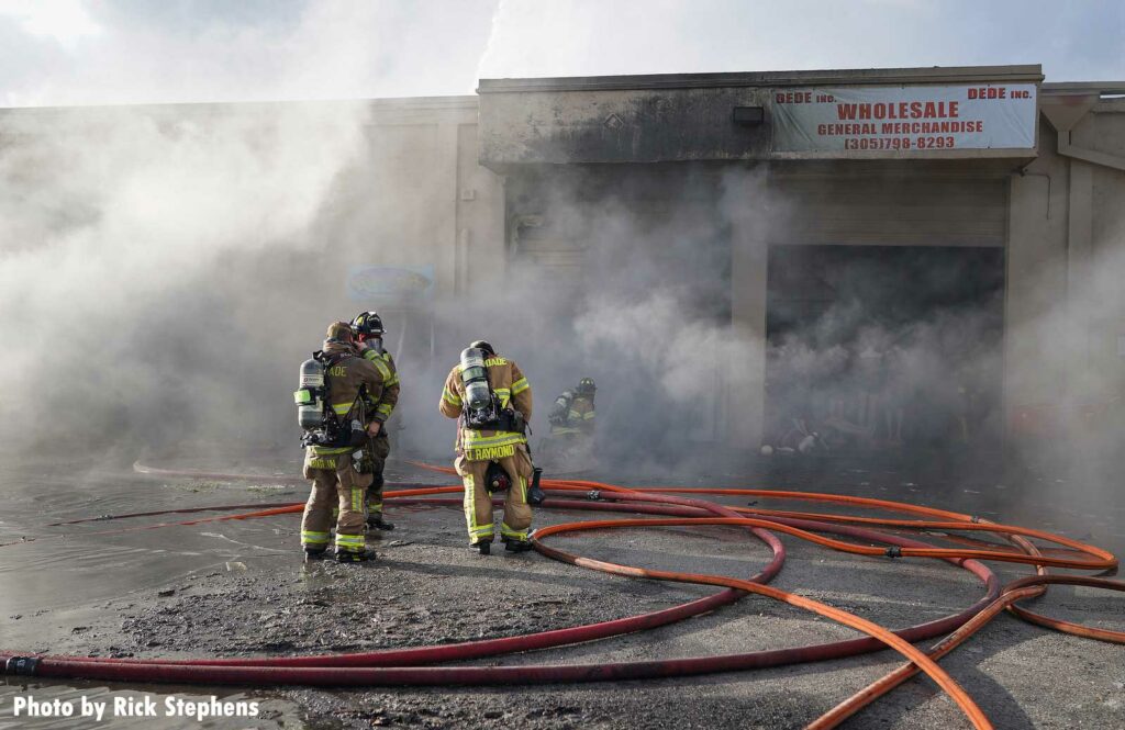 Firefighters and hoseline standing in the smoke at warehouse fire