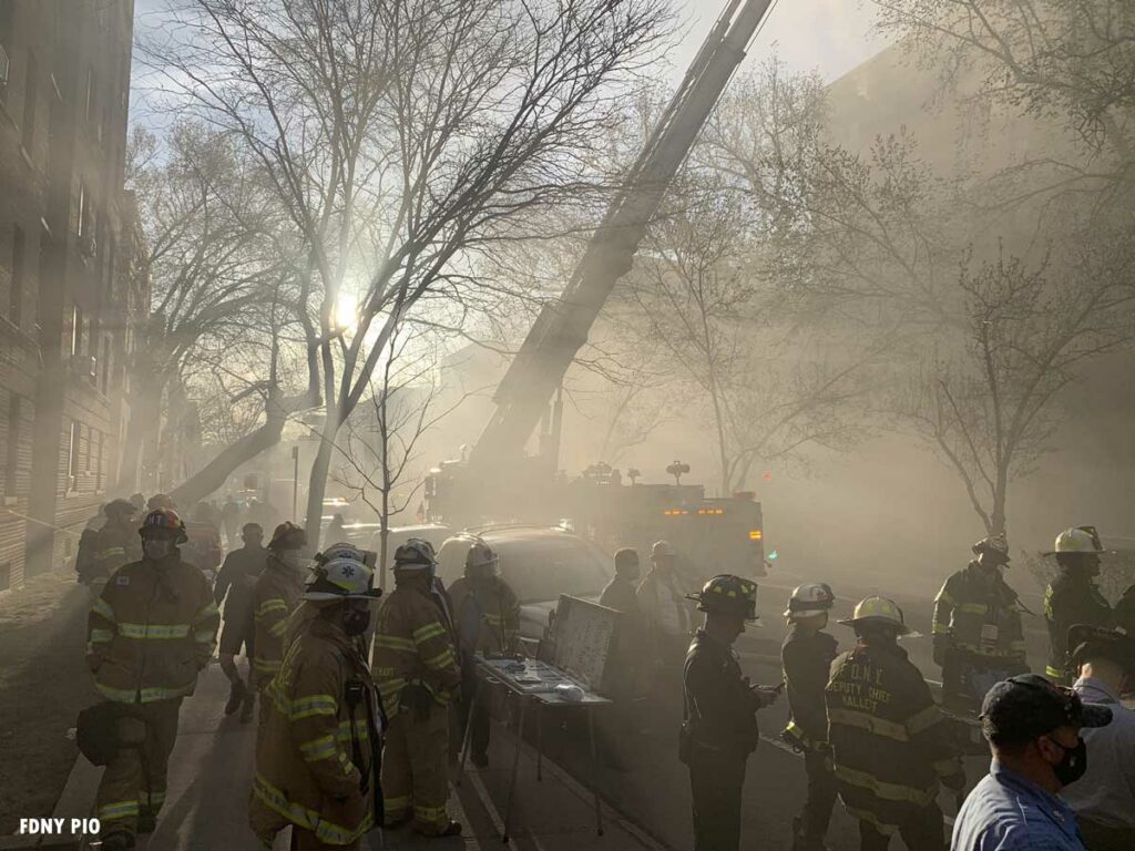 Sun through the mist with FDNY firefighters and command post and aerial in the background