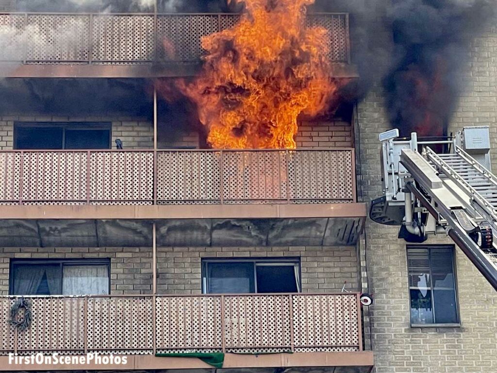 Firefighters at work at an apartment fire in Hempstead, New York, with flames ripping from balcony