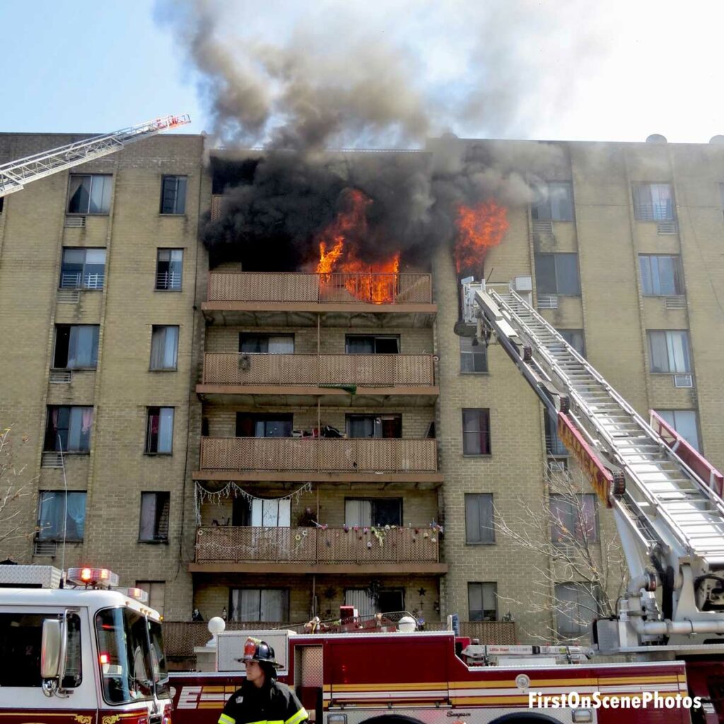 Fire burns on balcony at multi-story apartment in Hempstead with tower ladder and aerial ladder operating