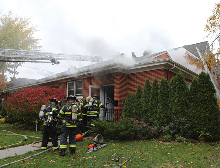 Firefighters prepare to enter the building to do a search and also stretch a second line into the building to combat fire in the basement.