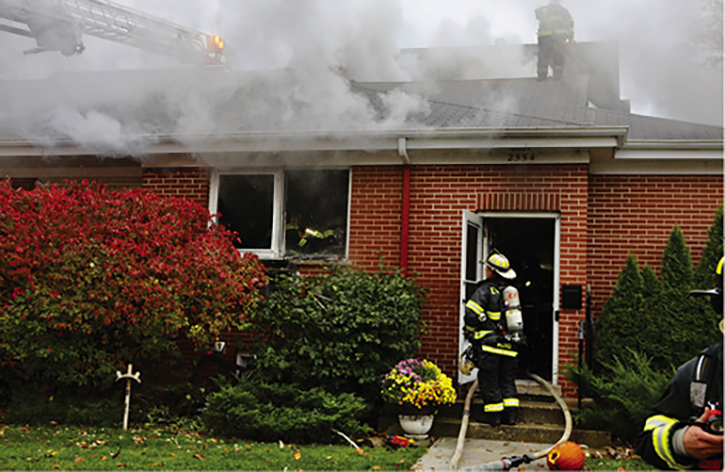 The chief stands out front observing conditions. You can also see under the windows where the main body of fire was; the basement window that was showing fire was hidden by the bushes. The importance of doing a 360° walk-around and looking both up and down cannot be overemphasized.