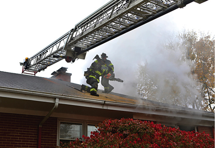 The firefighter on the roof with the saw is giving way to a member who is going to open up the hole using hand tools. 