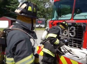 Firefighters set up an impromptu decon station using a hoseline