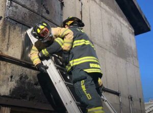 Firefighter locking another member into a ladder