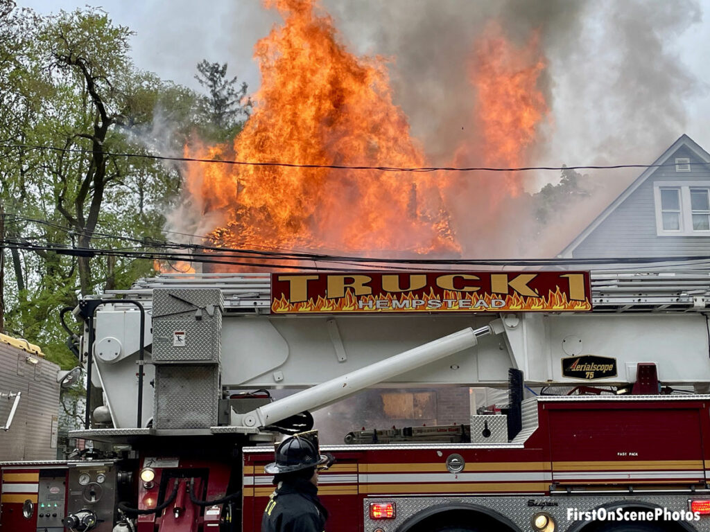 Truck one parked in front of a home as flames rage up to the skies in the background