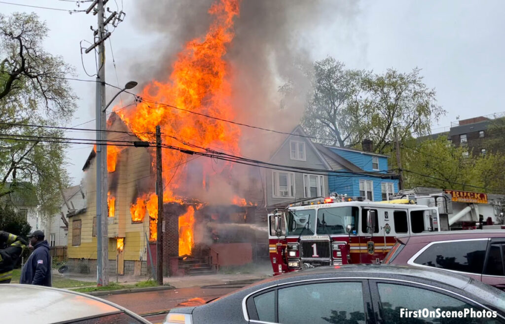 Flames tear through a home on the corner in Hempstead, New York, with a fire apparatus in front