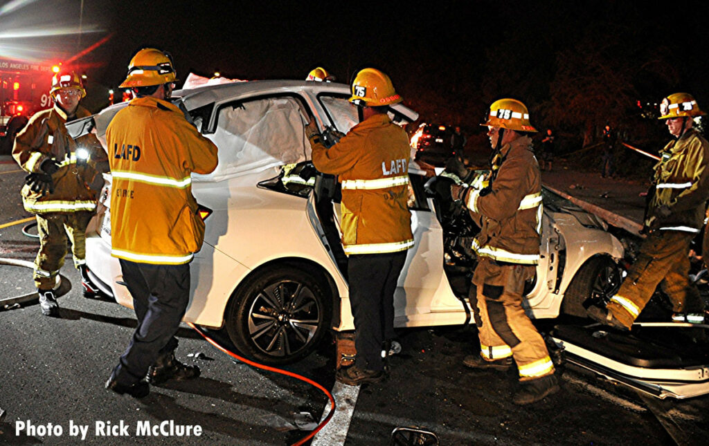 Firefighters lift the roof off a vehicle at crash scene