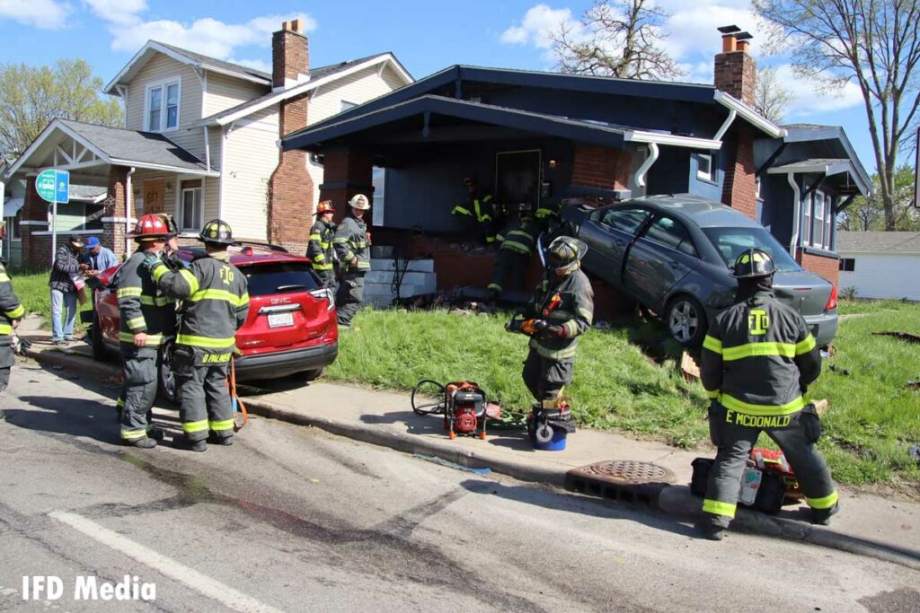 Firefighters at the scene of a crash that sent one vehicle into a porch