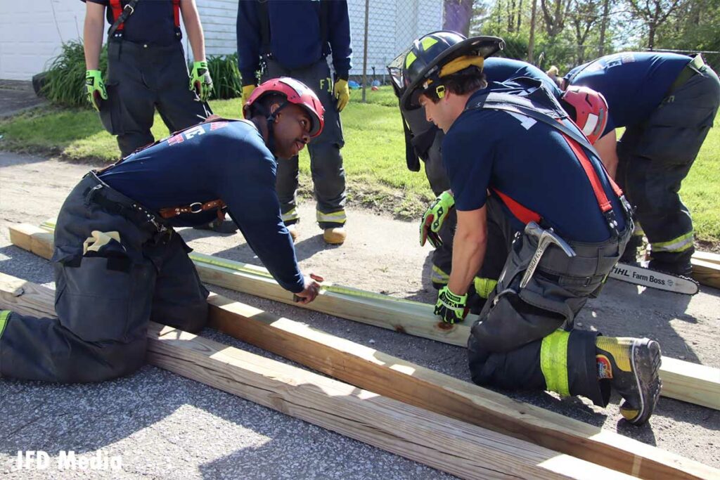 Firefighters consult while constructing a shoring mechanism