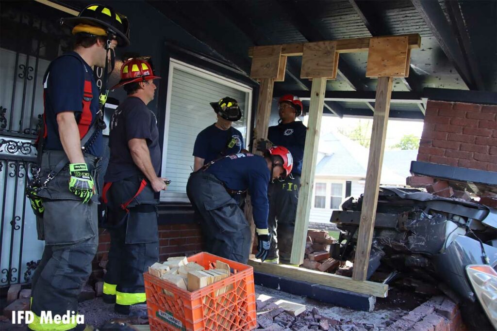 Firefighters place the shoring device in place on the damaged porch