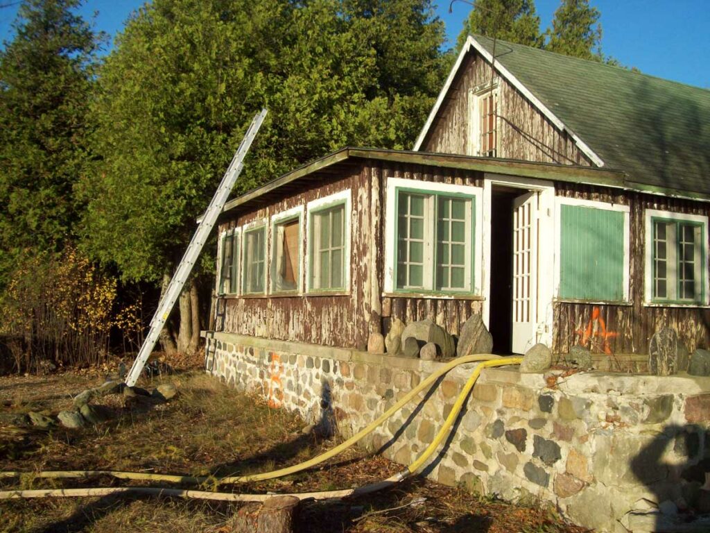 Ground ladder raised above roofline and two hoselines