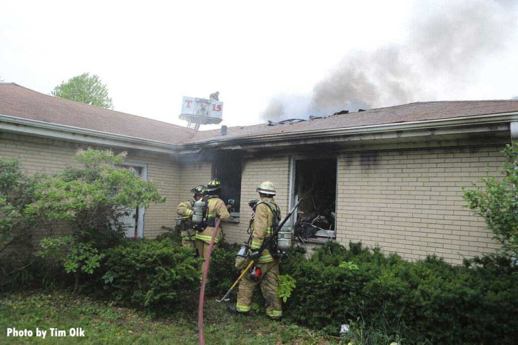 Firefighters put a hoseline through a window of the home