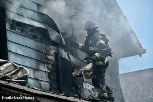 Firefighter performs overhaul on exterior of home amid smoke