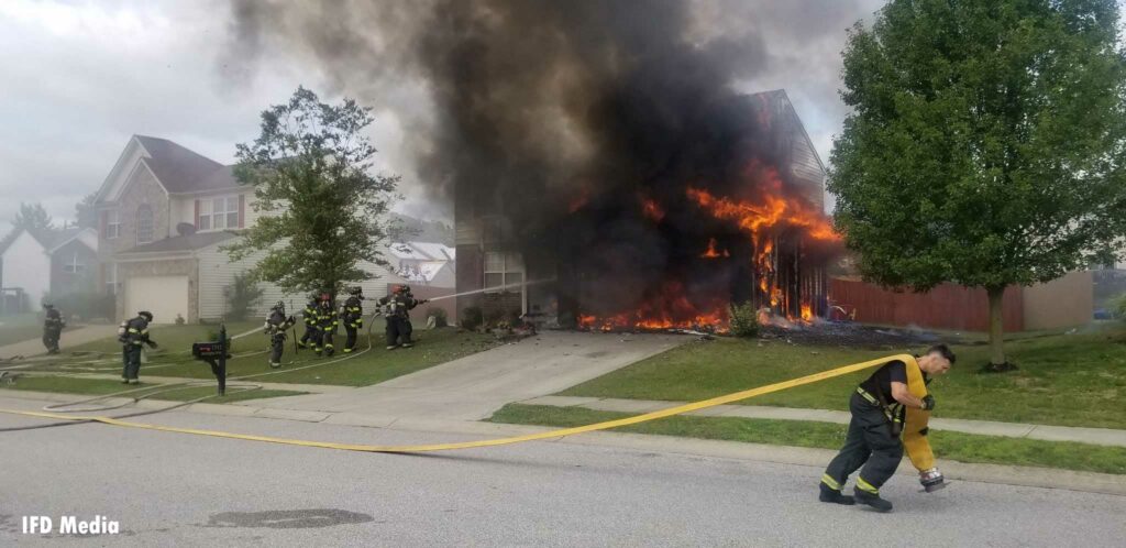 A firefighter drags a supply line at a house fire