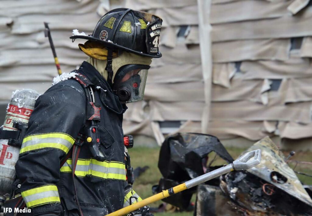 A firefighter in full gear and SCBA with a hook