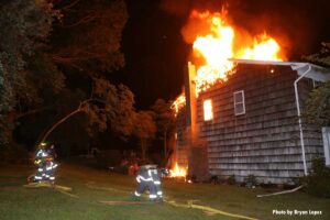 Firefighters flake out a hoseline at a burning home on Long Island