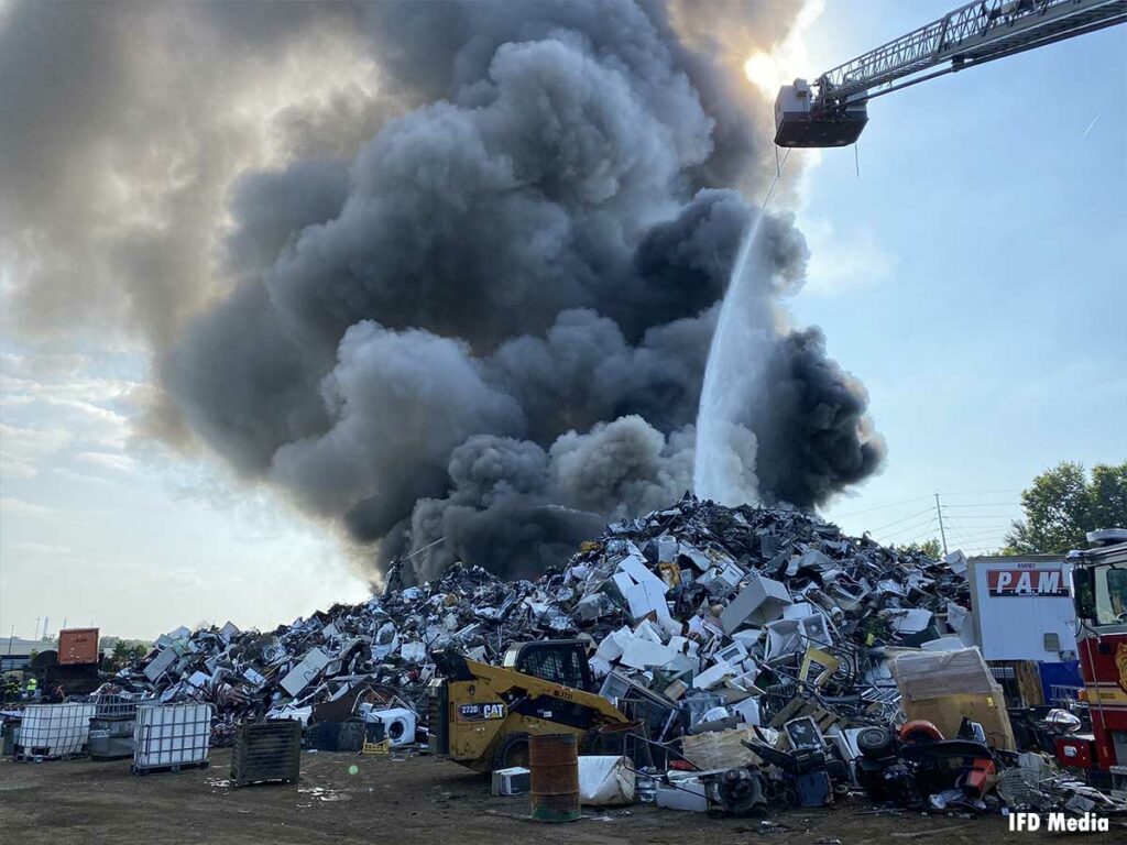 Tower ladder pours an elevated stream on burning scrap metal