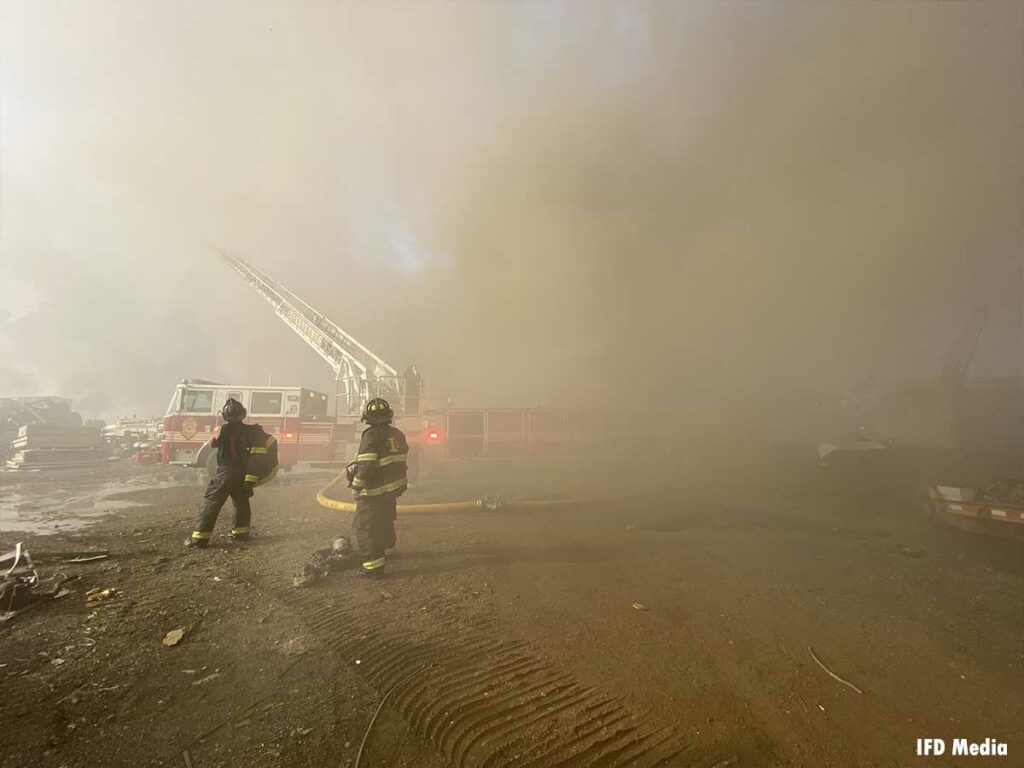 Firefighters, LDH, and tiller truck at Indianapolis scrap metal fire