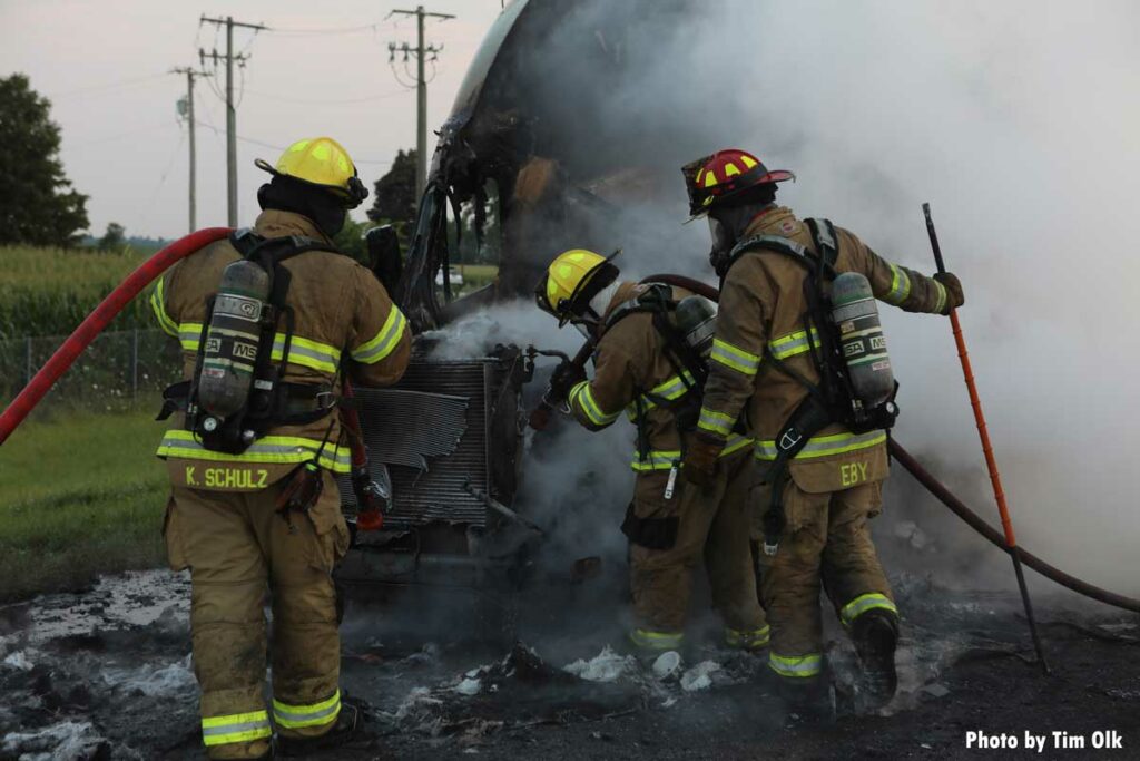 Firefighters put two hoselines on burned semi cab