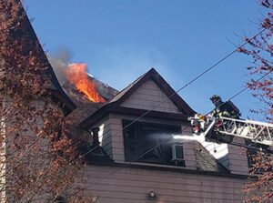 Firefighter on an aerial fighting fire in a Queen Anne-style home