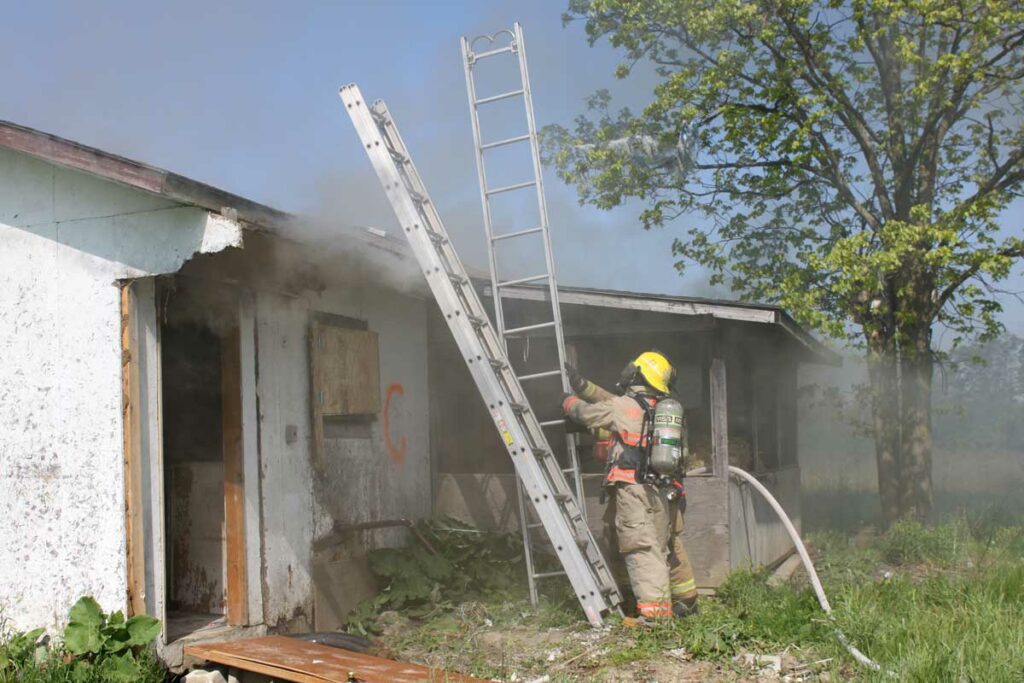 Firefighter with multiple portable ladders at house fire